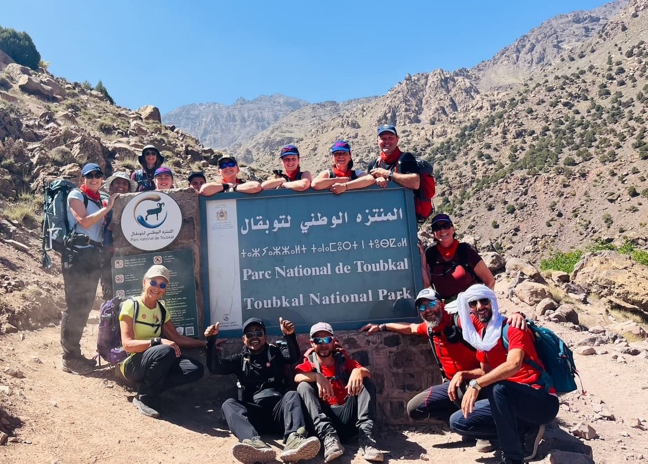 A trekking group gathered around the Toubkal National Park entrance sign